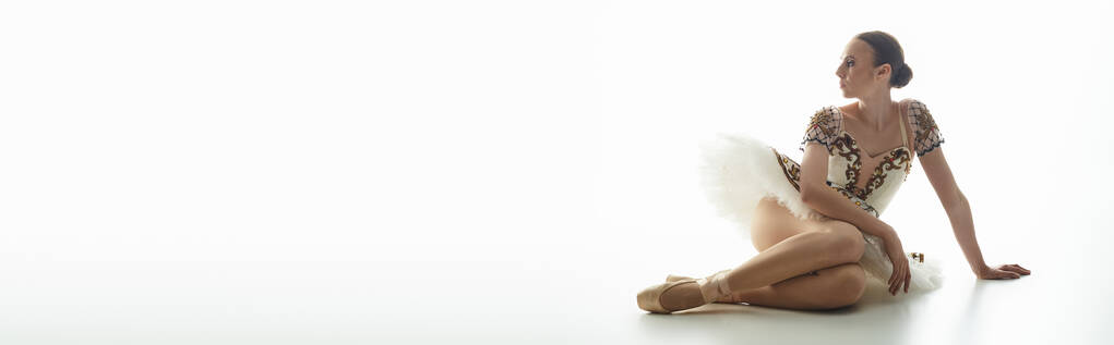 Eine junge Ballerina sitzt im Schneidersitz auf dem Boden. - Foto, Bild