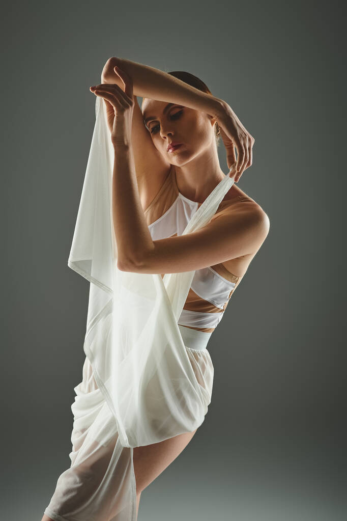 Una giovane ballerina vestita di bianco affascina con la sua graziosa danza del velo. - Foto, immagini