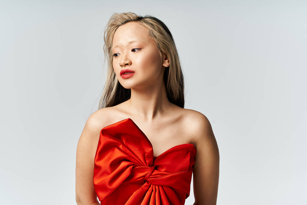 Mulher asiática vibrante em vestido vermelho marcando uma pose confiante. - Foto, Imagem