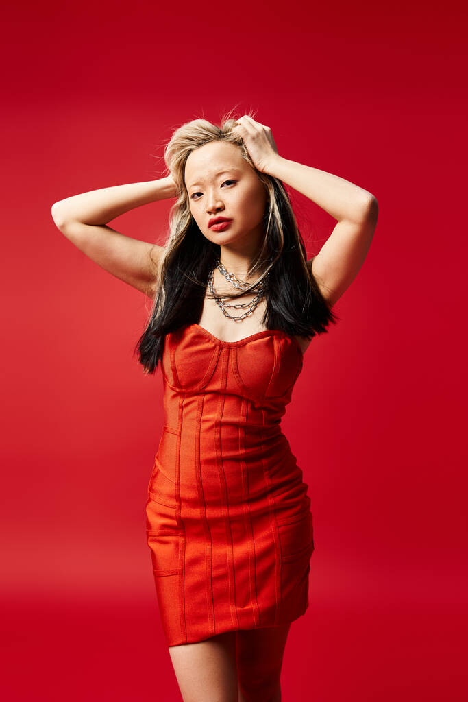 Приваблива азіатська жінка позує витончено в разючій червоній сукні. - Фото, зображення