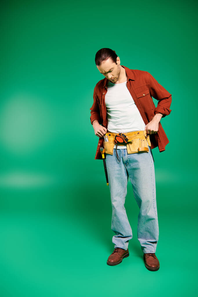 Чоловік у формі стоїть впевнено тримаючи інструменти на фоні пишного зеленого кольору. - Фото, зображення