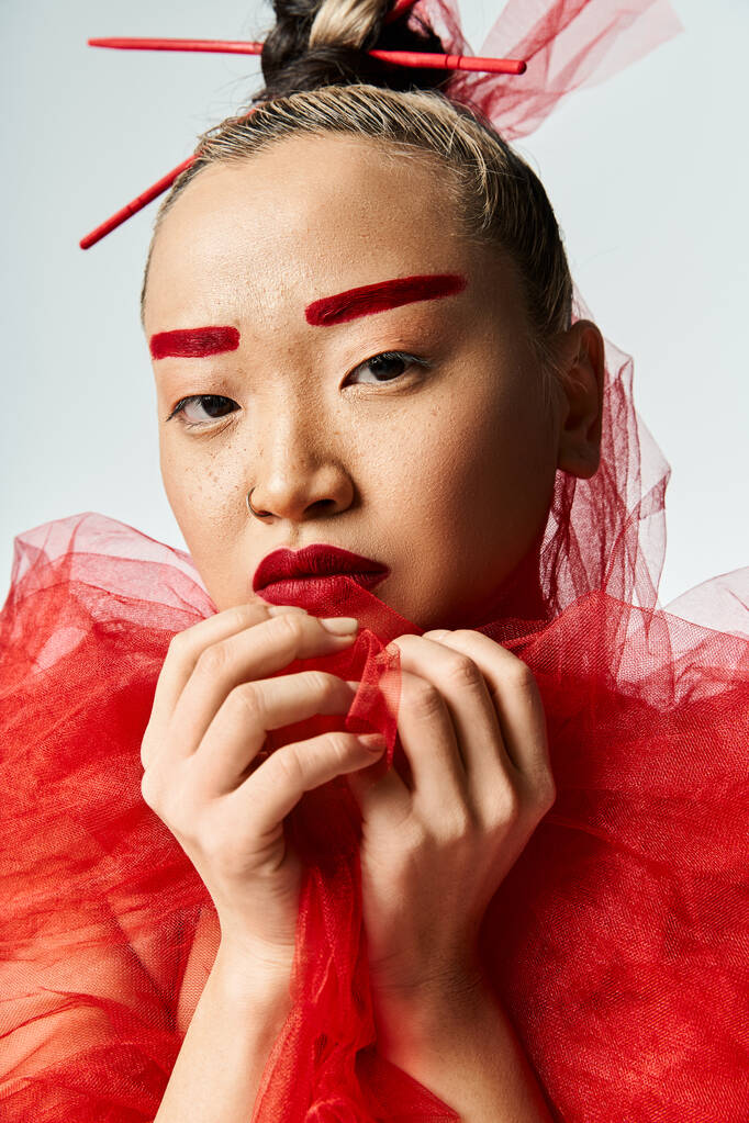 Aziatische vrouw in opvallende rode make-up en jurk poseren energiek. - Foto, afbeelding