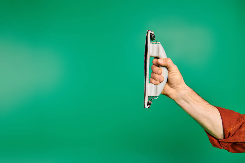 Una mano enfocada, sosteniendo un pulidor sobre un vibrante fondo verde. - Foto, Imagen
