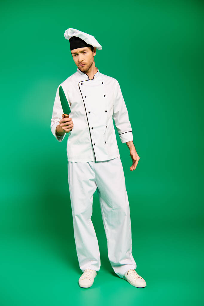 Een charismatische mannelijke chef-kok in wit uniform vol vertrouwen zwaaiend met een mes. - Foto, afbeelding