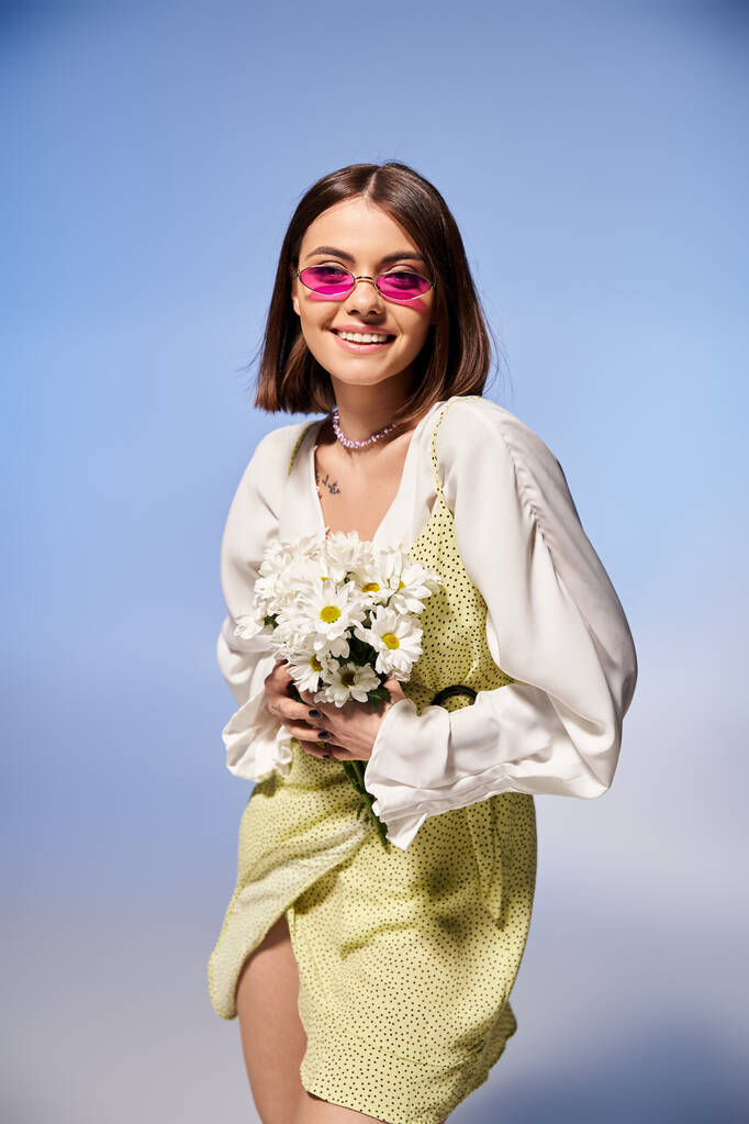 Zarif elbiseli esmer kadın stüdyoda canlı bir buket çiçek tutuyor.. - Fotoğraf, Görsel