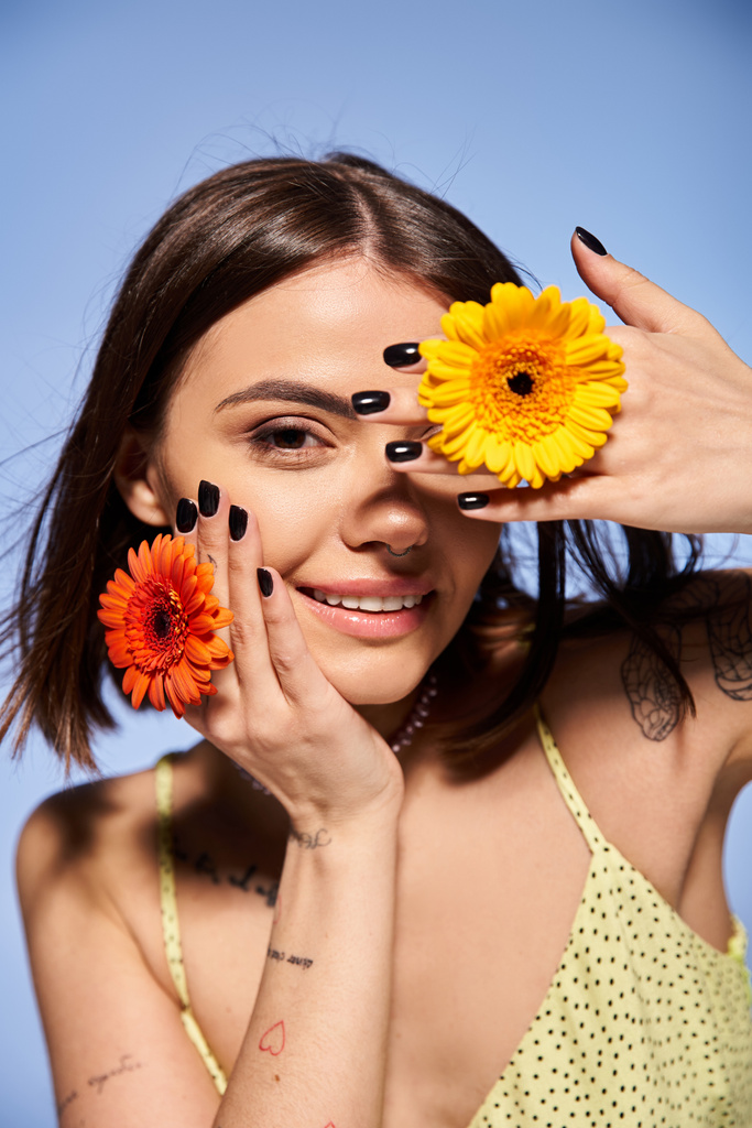 Молодая женщина с брюнетками держит нежный цветок перед лицом, демонстрируя элегантность и изящество. - Фото, изображение