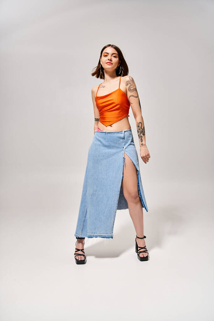 A brunette woman in a stylish skirt and top strikes a confident pose in a studio setting. - Photo, Image