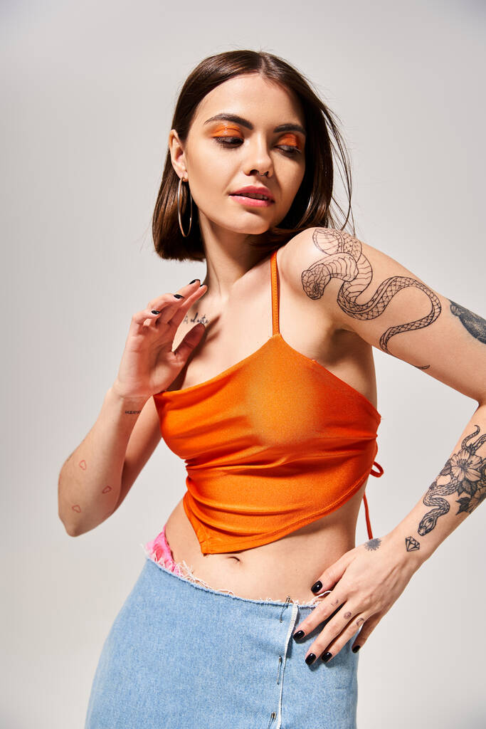 Una mujer joven con el pelo moreno orgullosamente mostrando un tatuaje llamativo en su brazo en un entorno de estudio creativo. - Foto, imagen