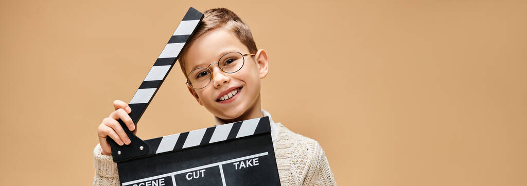 Niño preescolar imita a un director de cine con tablero de aplausos. - Foto, imagen