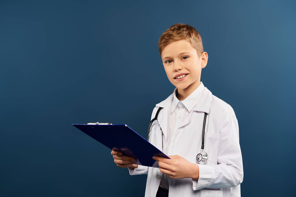 Mladý chlapec v lékařském kabátě psaní na podložce. - Fotografie, Obrázek