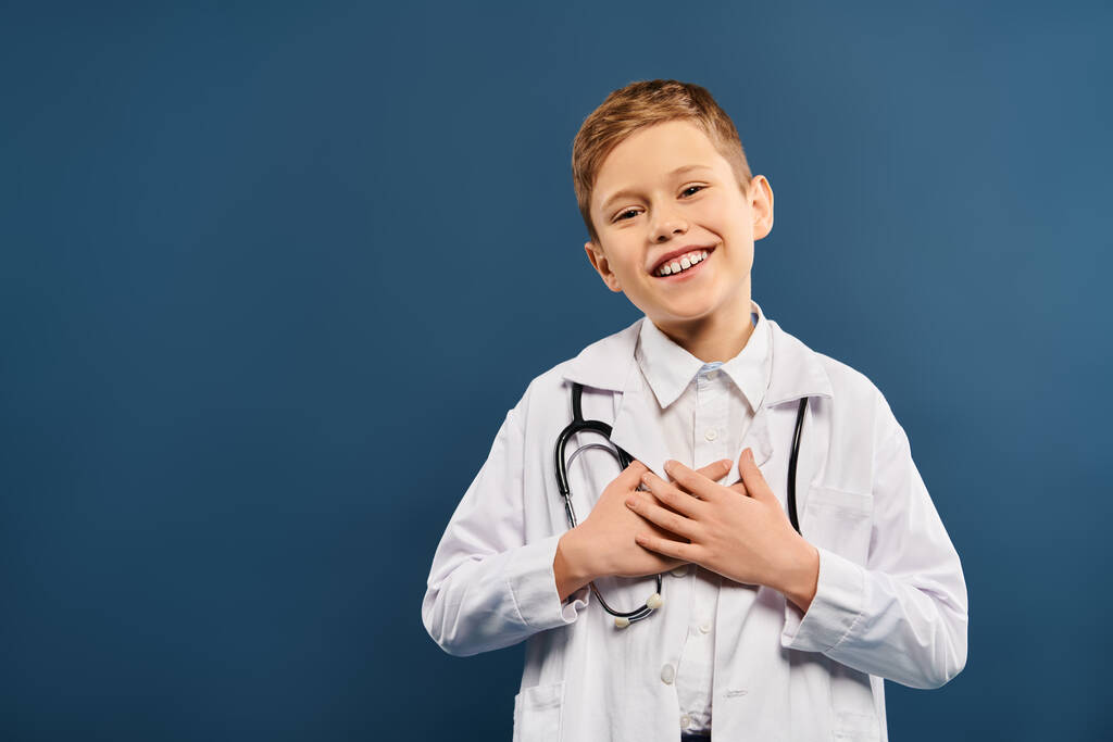 Jonge jongen in dokters jas en stethoscoop op blauwe achtergrond. - Foto, afbeelding