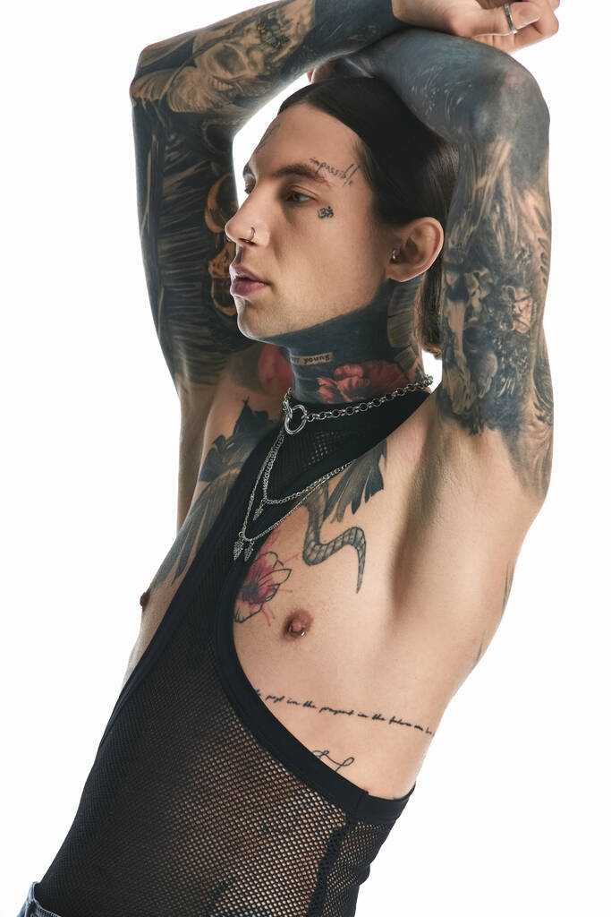 Un jeune homme élégant présente fièrement des tatouages complexes sur son bras et sa poitrine, exsudant l'expression artistique et l'individualité. - Photo, image