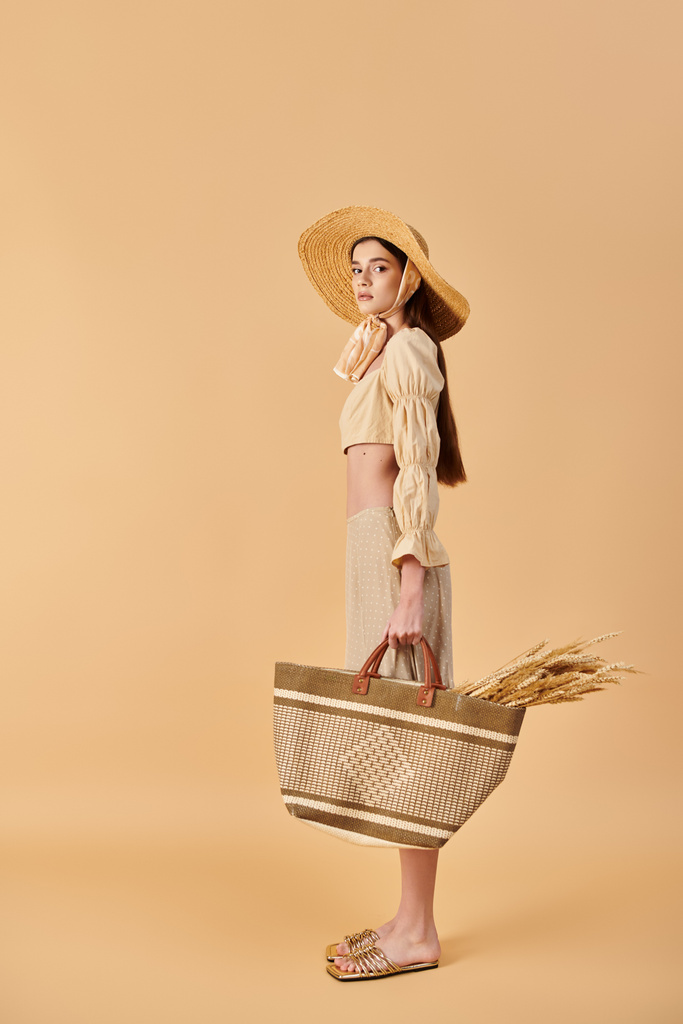 Молодая женщина с длинными брюнетками позирует в летнем наряде, носит соломенную шляпу и держит корзину. - Фото, изображение