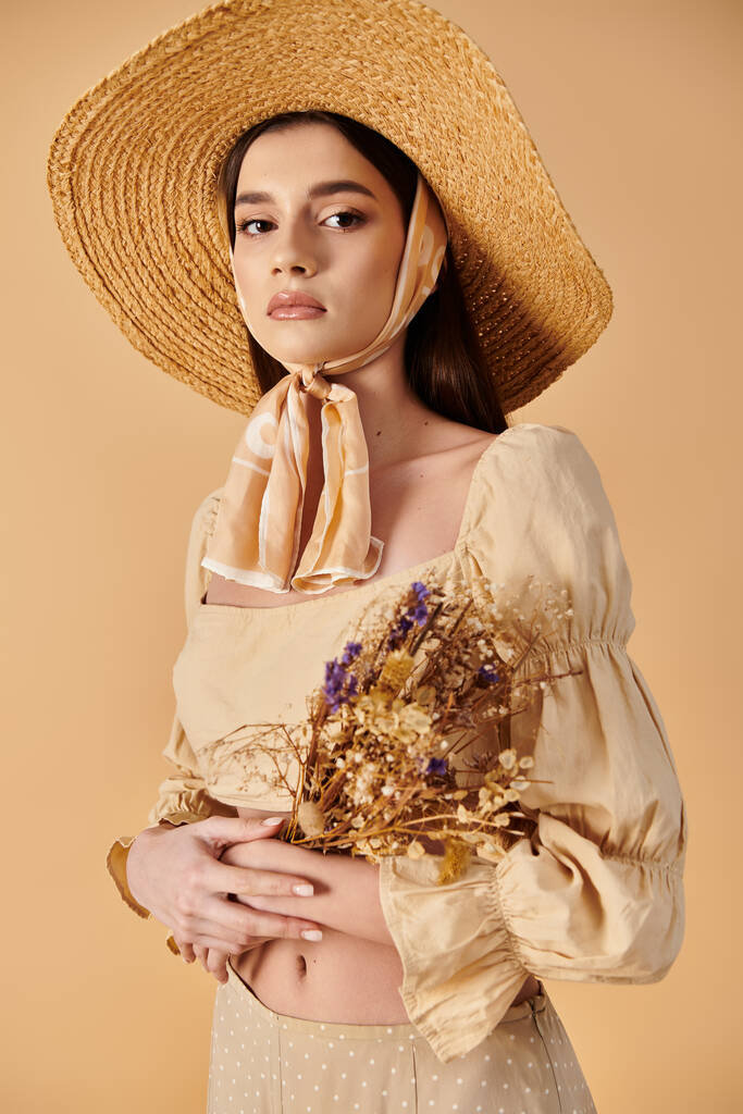 A young woman with long brunette hair exudes a summer vibe as she holds a bouquet of flowers wearing a straw hat. - Photo, Image