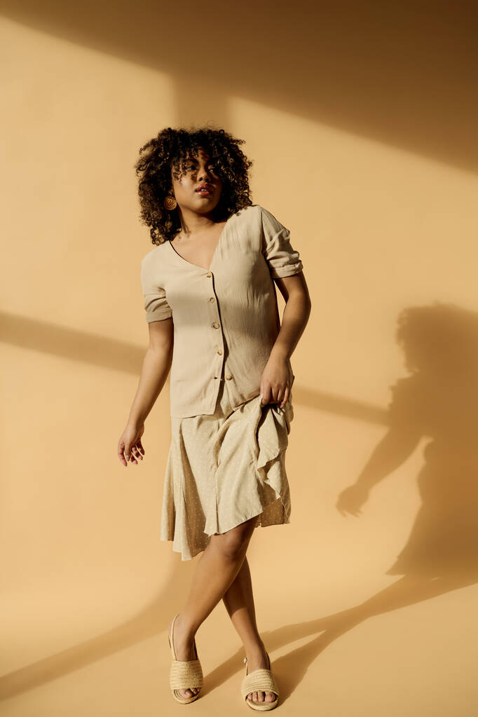 Krásná mladá Afroameričanka s kudrnatými vlasy stojí v místnosti a vrhá nápadný stín na zeď. - Fotografie, Obrázek