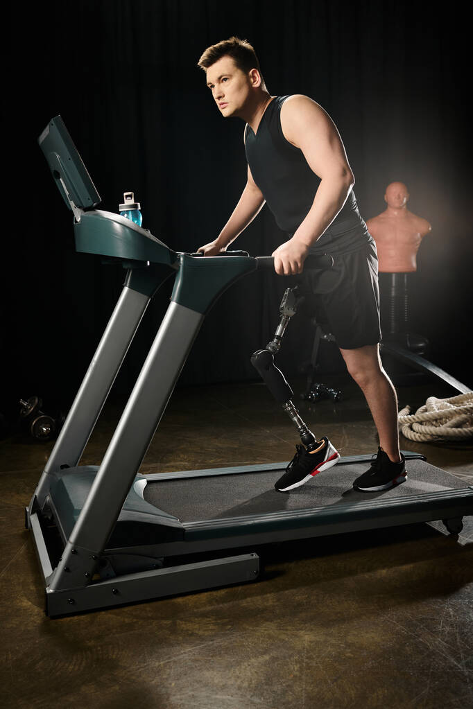 Ein behinderter Mann mit Beinprothese läuft auf einem Laufband in einem schwach beleuchteten Fitnessstudio und pusht sich, um seine Fitnessziele zu erreichen. - Foto, Bild