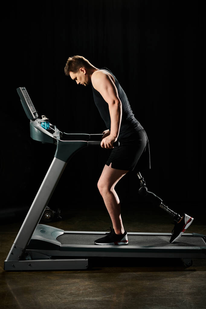 Een man met een kunstbeen loopt op een loopband in een fitnessruimte, toont vastberadenheid en kracht in het overwinnen van obstakels. - Foto, afbeelding
