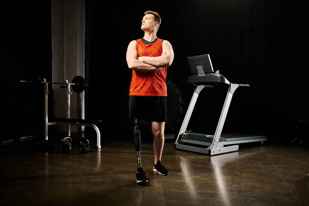 Egy eltökélt fogyatékos, műlábú férfi magabiztosan áll egy futópad előtt egy edzőteremben, készen az edzésre.. - Fotó, kép