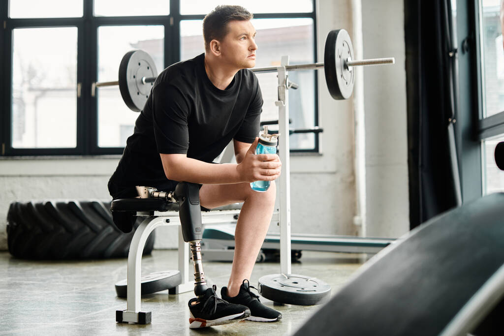 Ein Mann mit Beinprothese sitzt auf einer Bank und hält lässig eine Wasserflasche in der Hand. - Foto, Bild