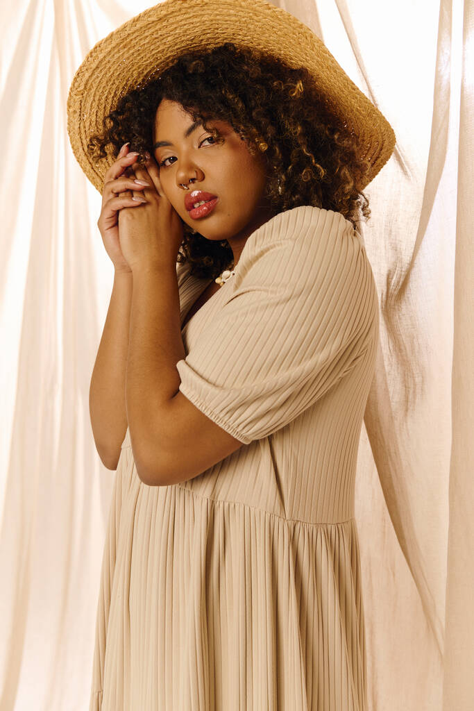 Kıvırcık saçlı, yaz elbisesi ve şapkası olan çekici bir Afro-Amerikan kadın bir portre için zarif bir poz veriyor.. - Fotoğraf, Görsel