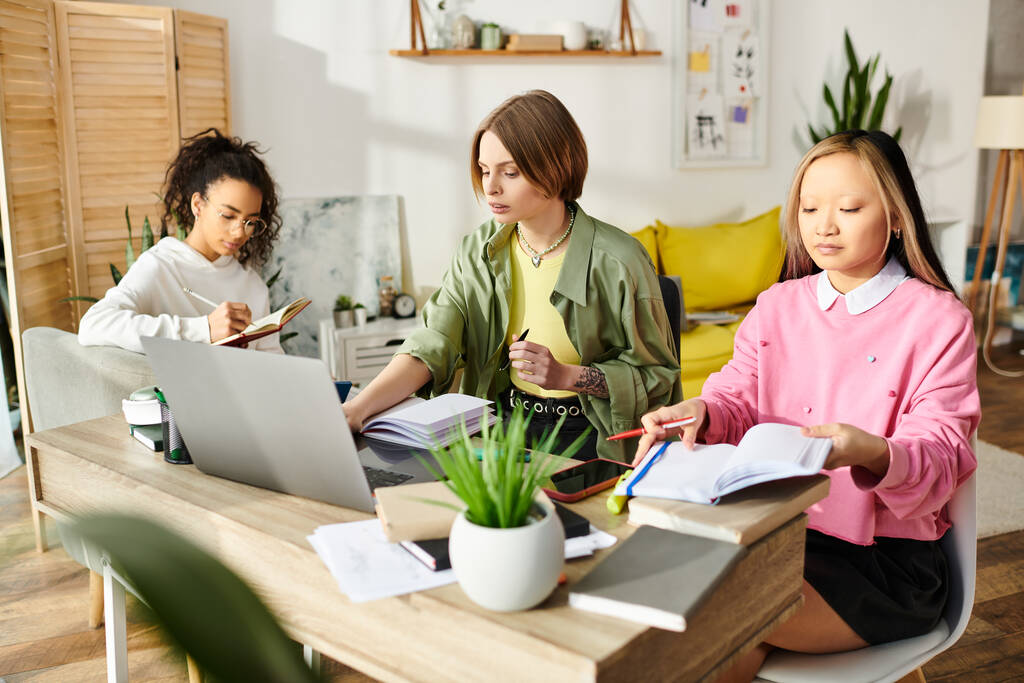 Três adolescentes interracial envolvidos em estudo focado sentado em uma mesa com laptops. - Foto, Imagem