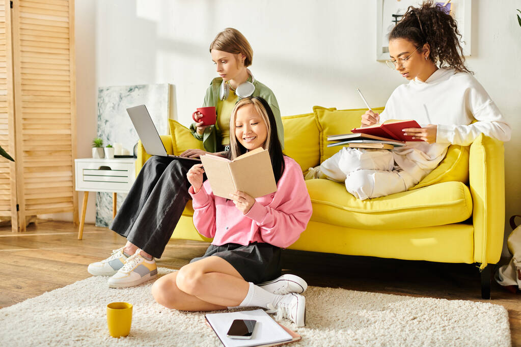Разнообразная группа девочек-подростков, сидящих рядом на ярко-желтом диване, сосредоточена на изучении и обмене моментами дружбы и образования. - Фото, изображение