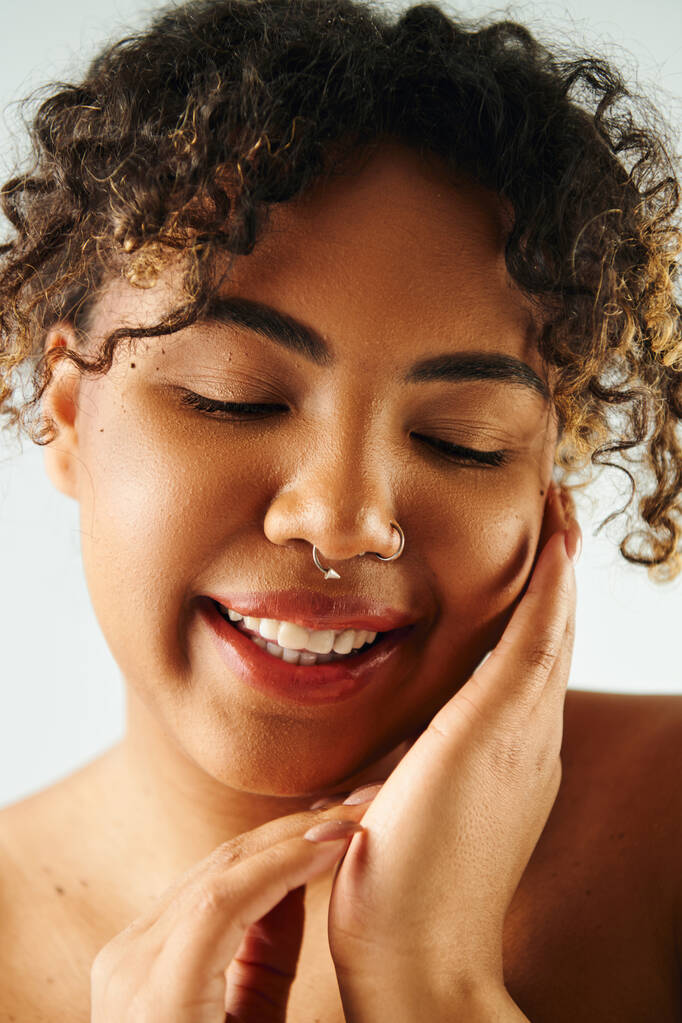Une belle femme afro-américaine posant avec un anneau de nez sur un fond vibrant. - Photo, image