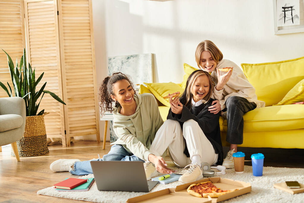 Teenager-Freundinnen mit unterschiedlichem Hintergrund sitzen auf dem Fußboden, vertieft in den Laptop-Bildschirm. - Foto, Bild
