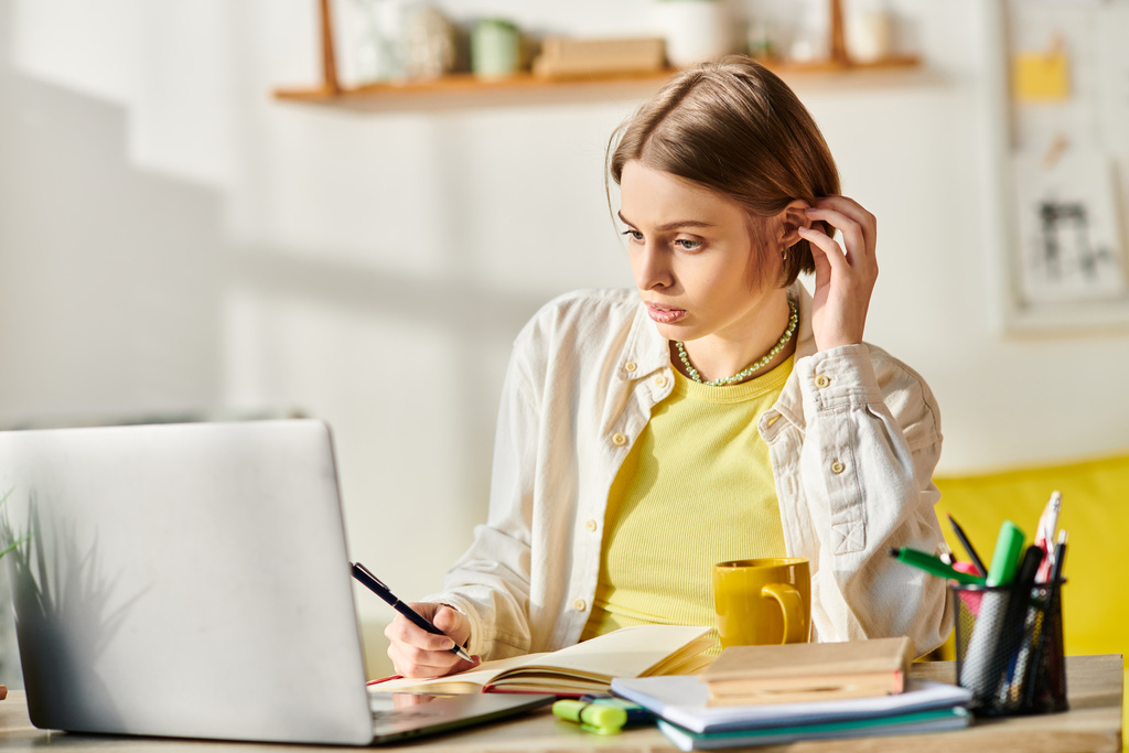 Une adolescente concentrée est assise à un bureau, absorbée par l'apprentissage en ligne avec son ordinateur portable, entourée de matériel d'étude. - Photo, image