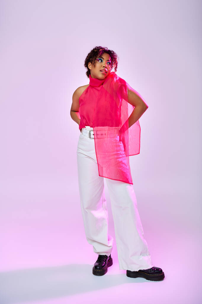 Яскрава афроамериканка позує в рожевій сорочці і білих штанях. - Фото, зображення