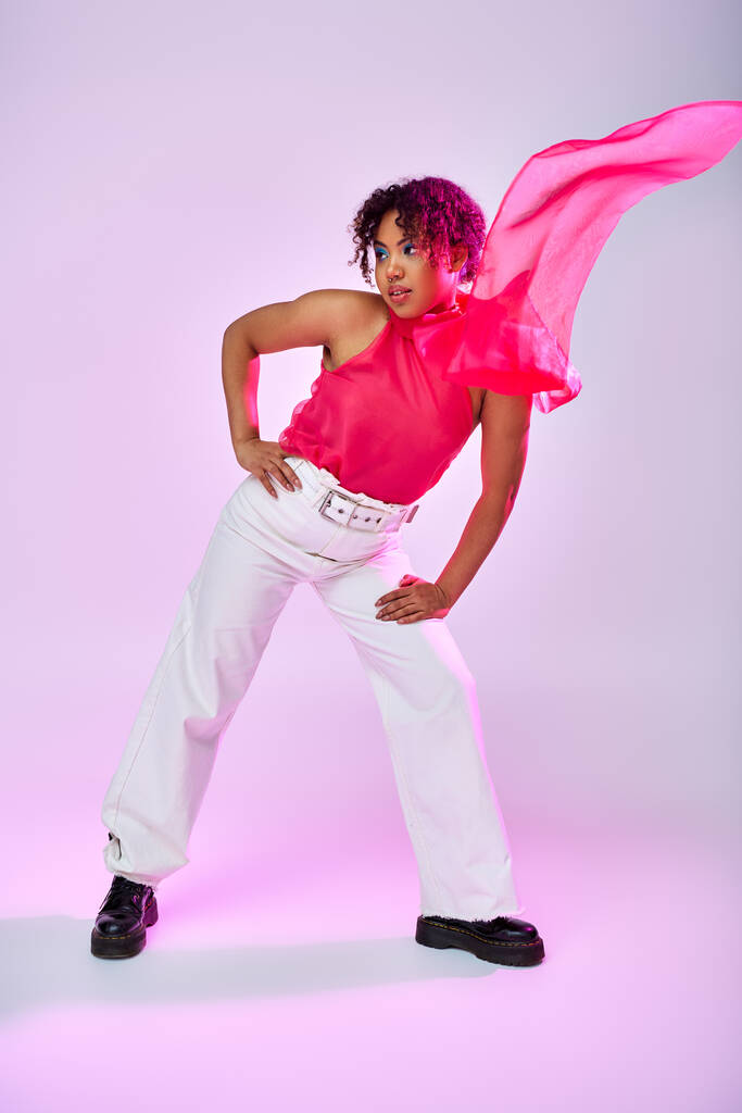 Afrikai amerikai nő pózol elegánsan fehér nadrág és rózsaszín ing élénk háttér. - Fotó, kép