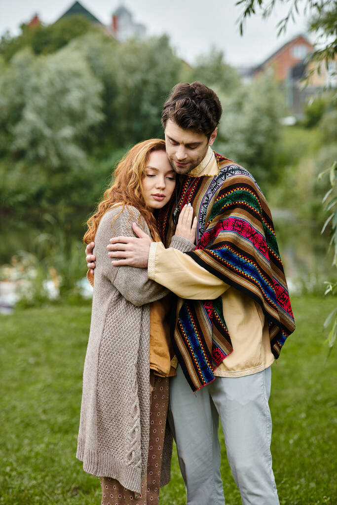 Un uomo e una donna in abito boho abbracciano teneramente in mezzo alla bellezza naturale di un parco verde, persi in un momento d'amore. - Foto, immagini