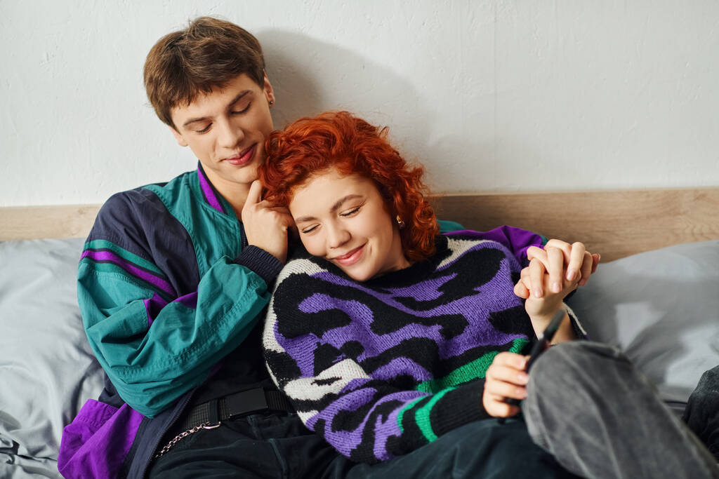 αγάπη δελεαστικό ζευγάρι σε φανταχτερά κομψά ρούχα αγκαλιάζει σαγηνευτικά στο κρεβάτι και χαμογελώντας ευτυχισμένοι - Φωτογραφία, εικόνα