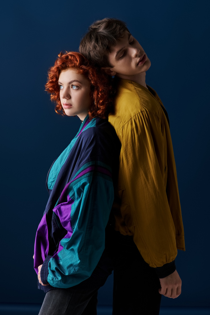 appealing boyfriend and girlfriend posing back to back and looking away on dark blue background - Photo, Image