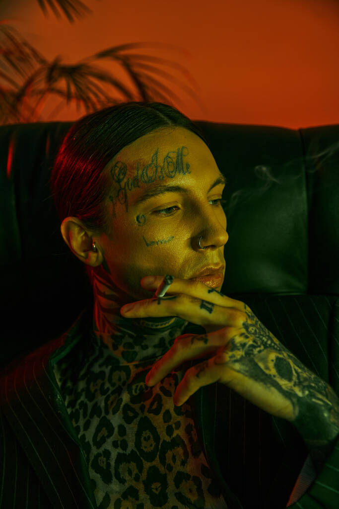 Un uomo con il viso tatuato che fuma una sigaretta - Foto, immagini