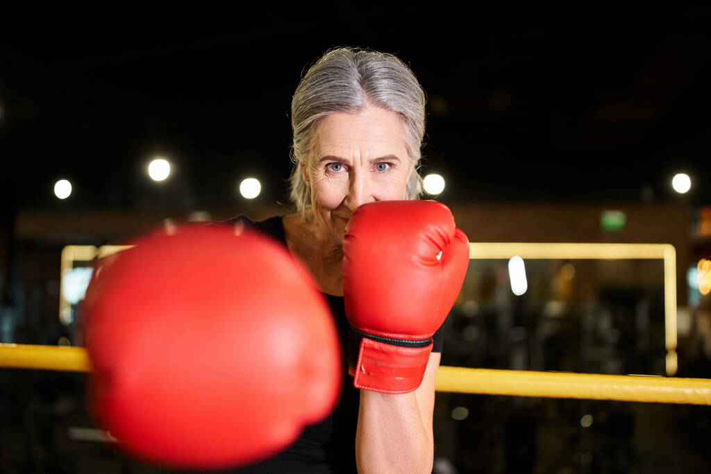 gyönyörű vidám idős nő sportruházat boksz kesztyű edzés gyűrű és mosoly a kamera - Fotó, kép