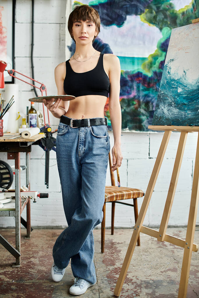 Uma mulher está na frente de uma pintura, segurando uma paleta. - Foto, Imagem