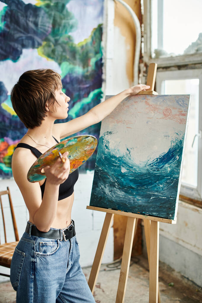 Žena se štětcem v ruce, zaměřená na malování obrazu. - Fotografie, Obrázek