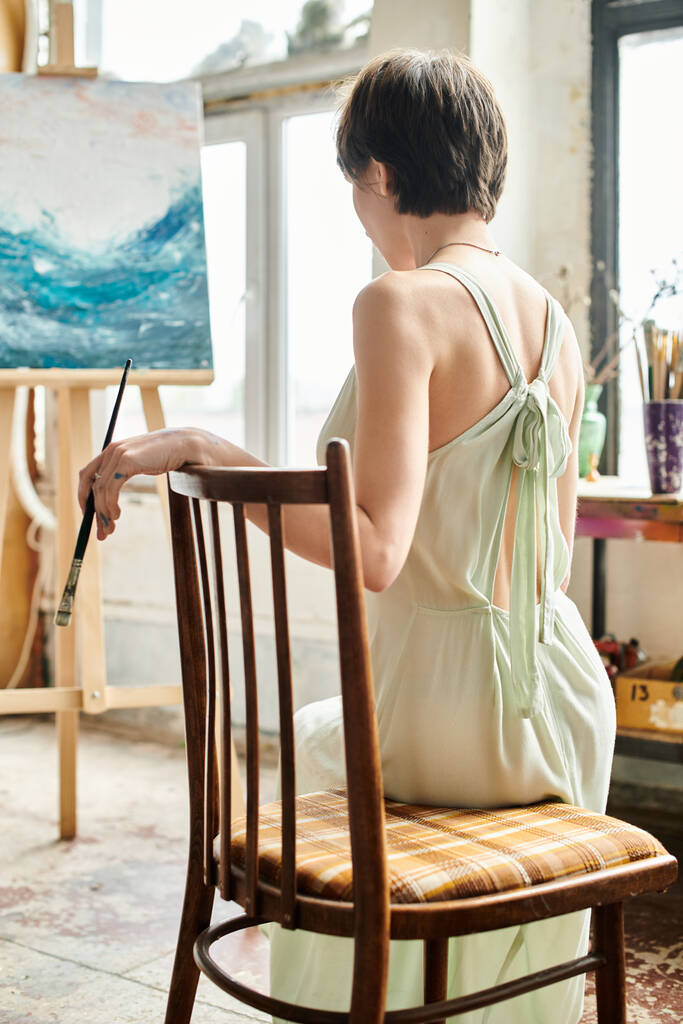 Žena sedí před obrazem na židli. - Fotografie, Obrázek