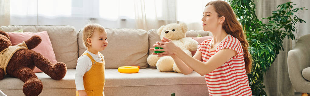 Uma jovem mãe se envolve com sua criança em uma sessão de brincadeira emocionante em casa. - Foto, Imagem