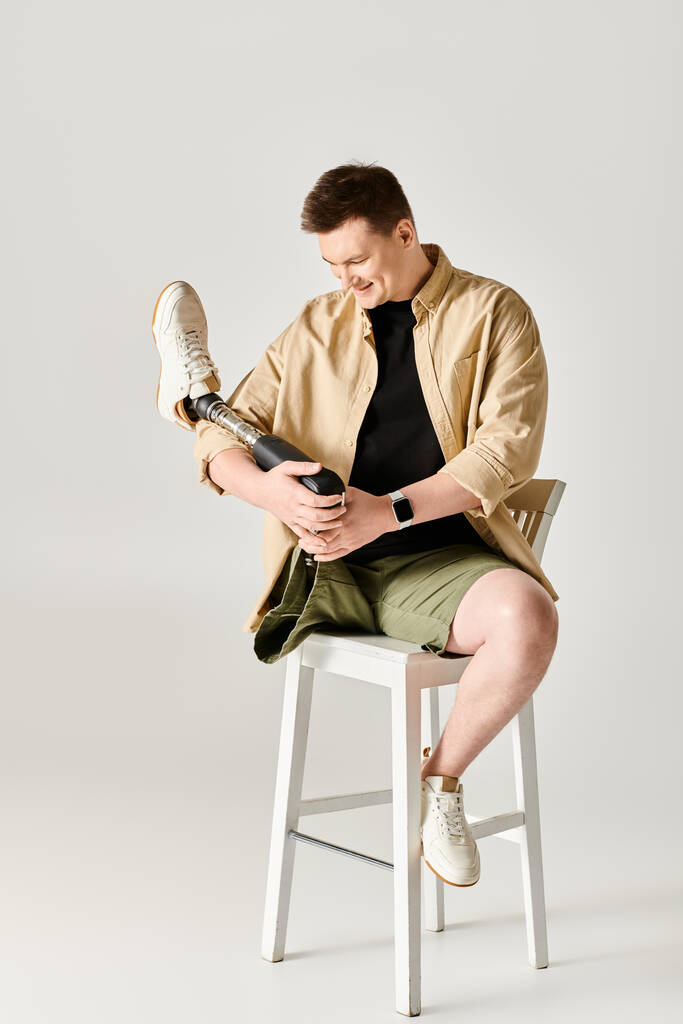 Ένας όμορφος άντρας με προσθετικό πόδι κάθεται σε ένα σκαμνί. - Φωτογραφία, εικόνα