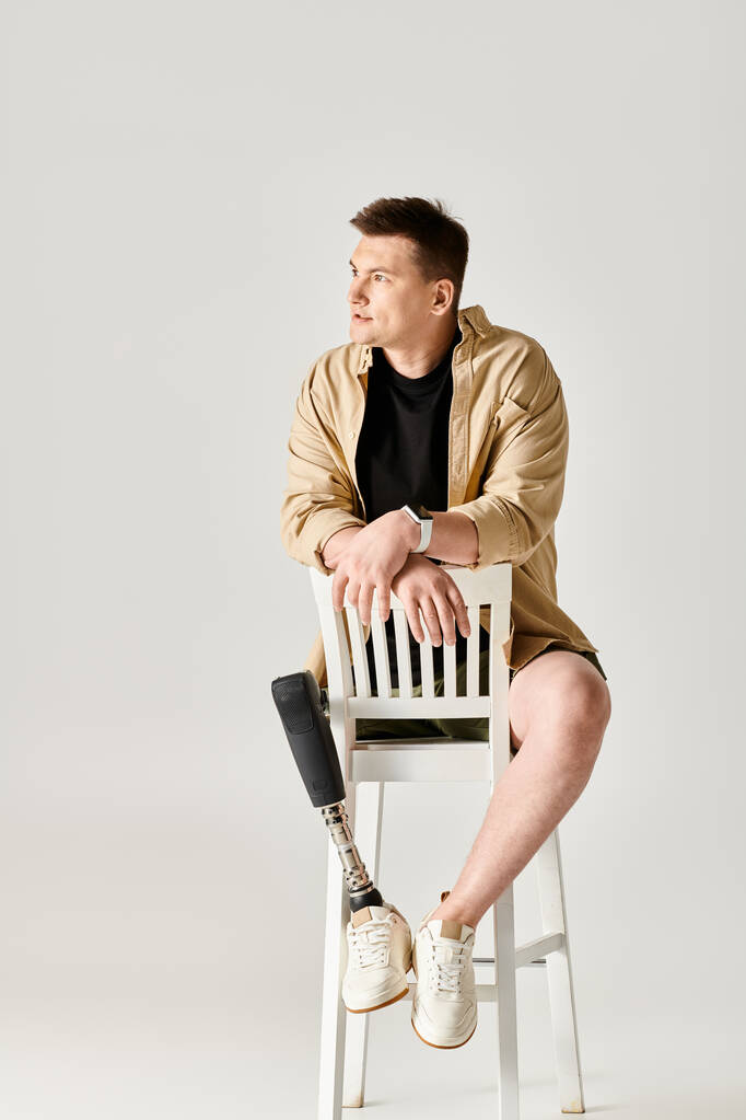 Komea mies, jolla on proteesijalka, istuu luottavaisesti valkoisen tuolin päällä.. - Valokuva, kuva