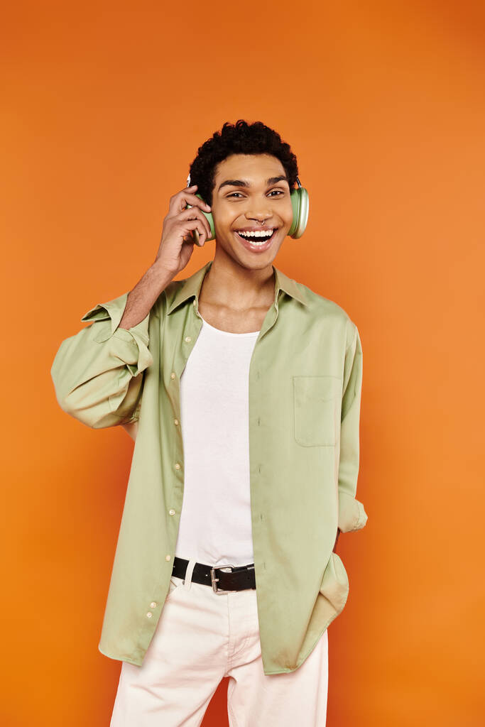 χαρούμενα κομψό αφροαμερικανός άνδρας σε casual ρούχα με ακουστικά και χαμογελώντας στην κάμερα ευτυχώς - Φωτογραφία, εικόνα