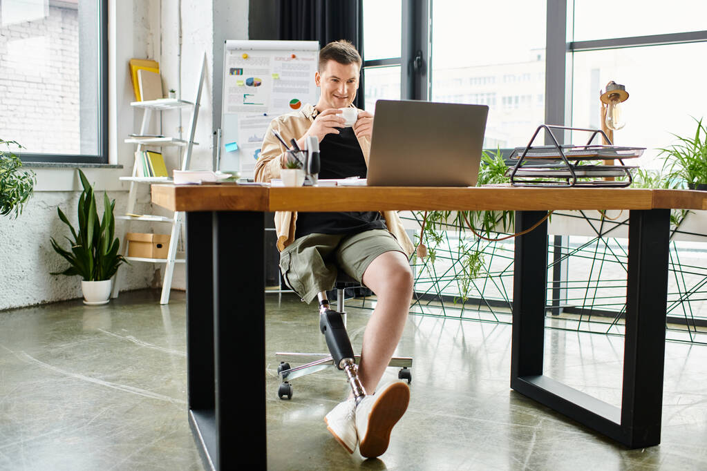 Un hombre de negocios guapo con una pierna protésica trabaja diligentemente en su portátil en un escritorio elegante. - Foto, imagen
