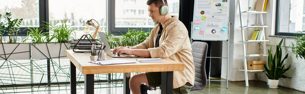 Bel homme d'affaires avec une jambe prothétique travaillant sur un ordinateur portable à son bureau. - Photo, image