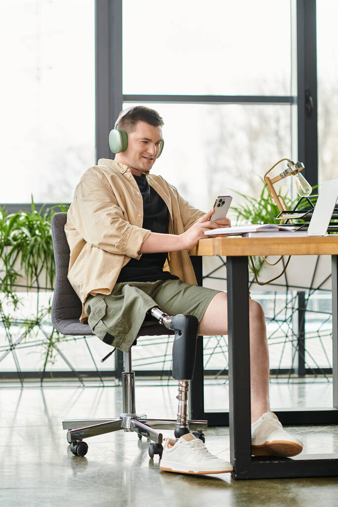 Un hombre de negocios con una pierna protésica se sienta en una mesa, enfocándose intensamente en la pantalla de su computadora portátil. - Foto, imagen