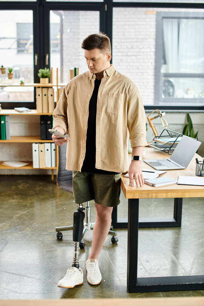 Ein schöner Geschäftsmann mit Beinprothese steht an einem Schreibtisch in einem geschäftigen Büro. - Foto, Bild