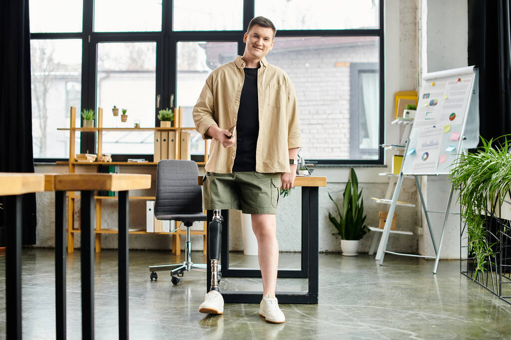 Красивый бизнесмен с протезной ногой стоит перед столом в современном офисе. - Фото, изображение