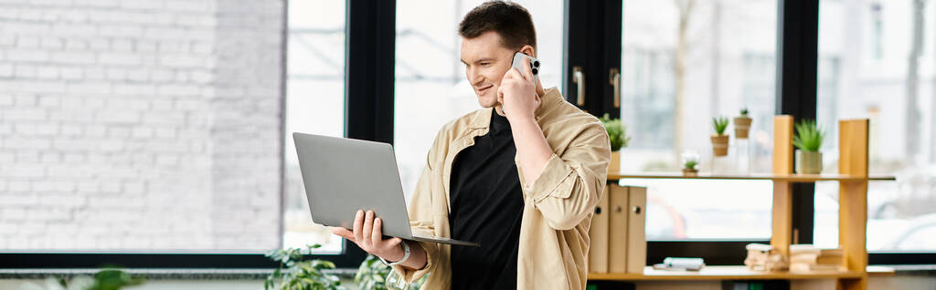 Ένας όμορφος επιχειρηματίας με προσθετικό πόδι αποτελεσματικά multitasking με ένα κινητό τηλέφωνο και φορητό υπολογιστή. - Φωτογραφία, εικόνα
