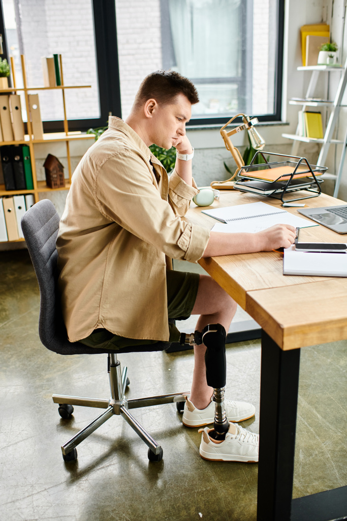Un hombre de negocios guapo con una pierna protésica trabajando en un portátil en su escritorio. - Foto, Imagen